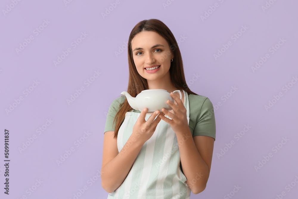 漂亮的年轻女人穿着围裙，淡紫色背景上有茶壶