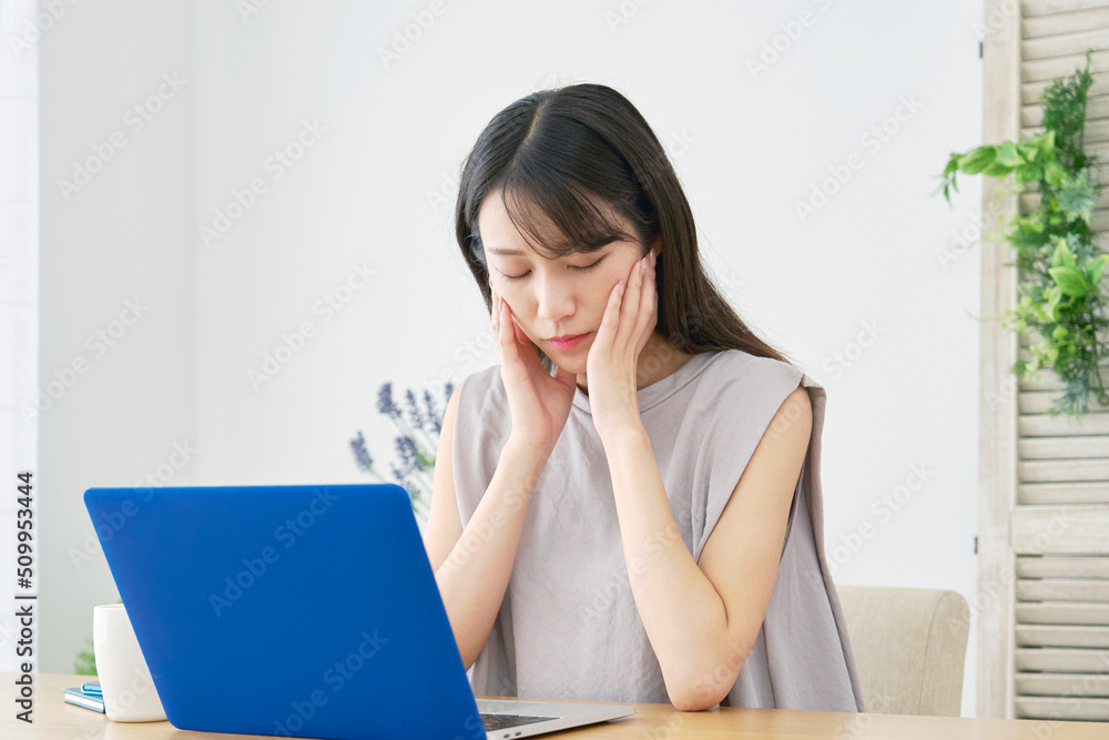 リビングでノートパソコンの前で疲れている女性