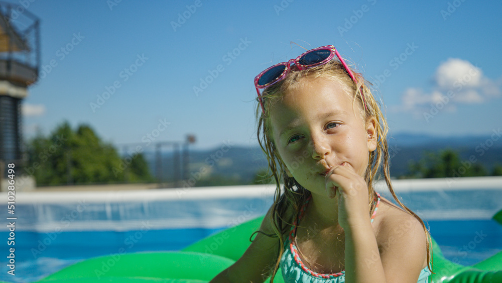 特写：可爱的小女孩在花园游泳池里吃完冰淇淋