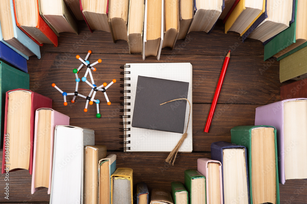 热爱科学概念。书籍的心形、研究生帽和木制桌子上的分子模型。拿一个d