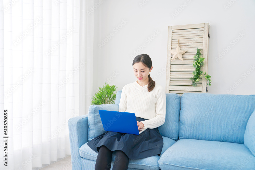リビングのソファーに座ってノートパソコンを使う女性