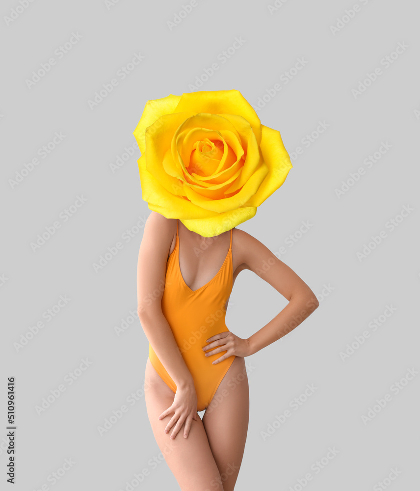 Woman with yellow rose flower instead of her head and in swimsuit on grey background