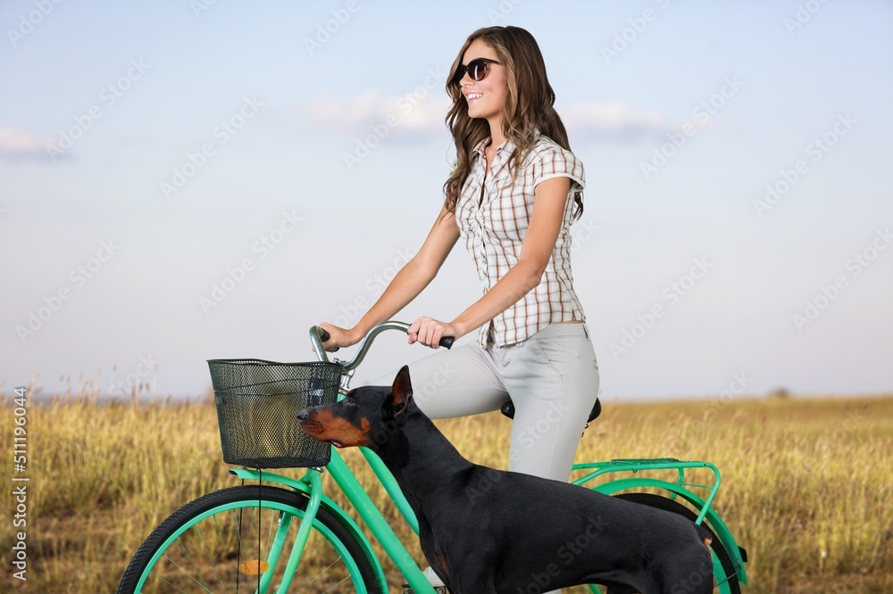一个女人和一只狗一起骑自行车。一个年轻女人和她的宠物一起骑自行车在附近跑步。旅行