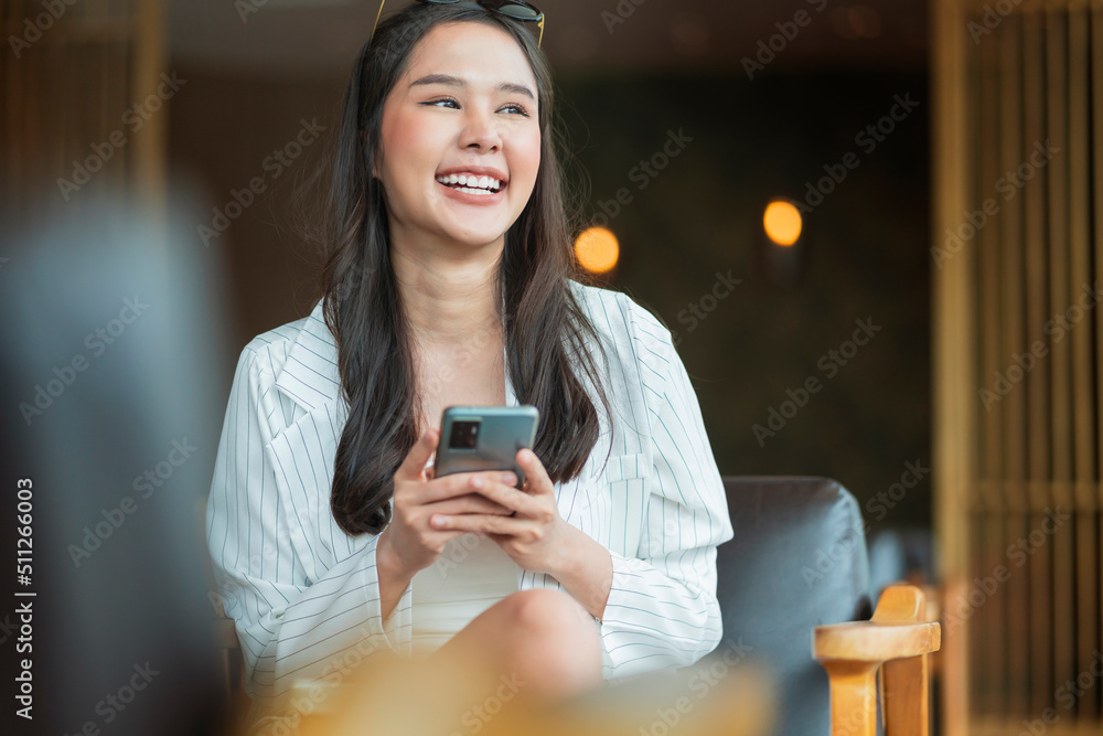 漂亮的年轻亚洲女人在咖啡店使用智能手机收到电子邮件短信关于他的好消息SME