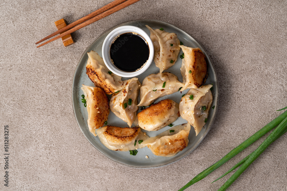 灰色桌子背景上放着酱油的锅里煎饺子饺子饺子。