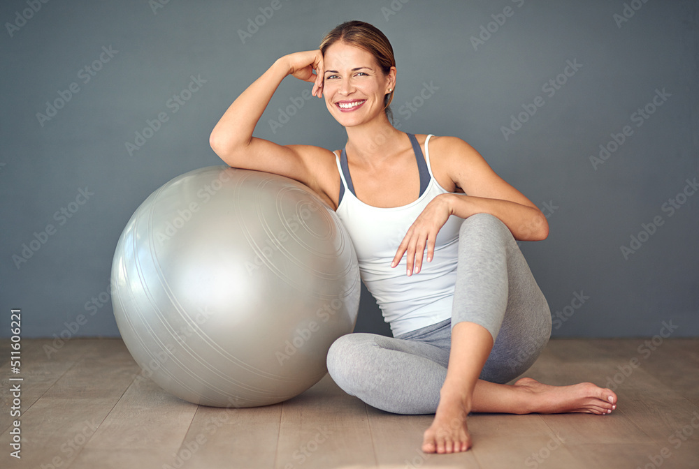 尽情享受吧。一个运动型年轻女子坐在健身球旁边的照片。