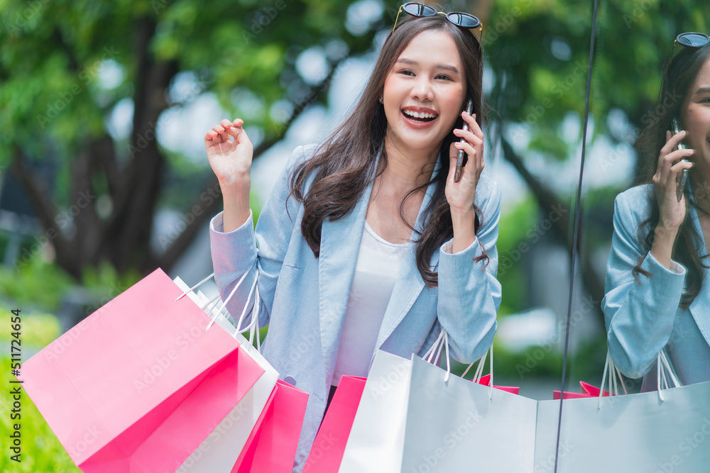 有魅力的亚洲女性喜欢积极的休闲购物手提纸袋和智能手机享受pu
