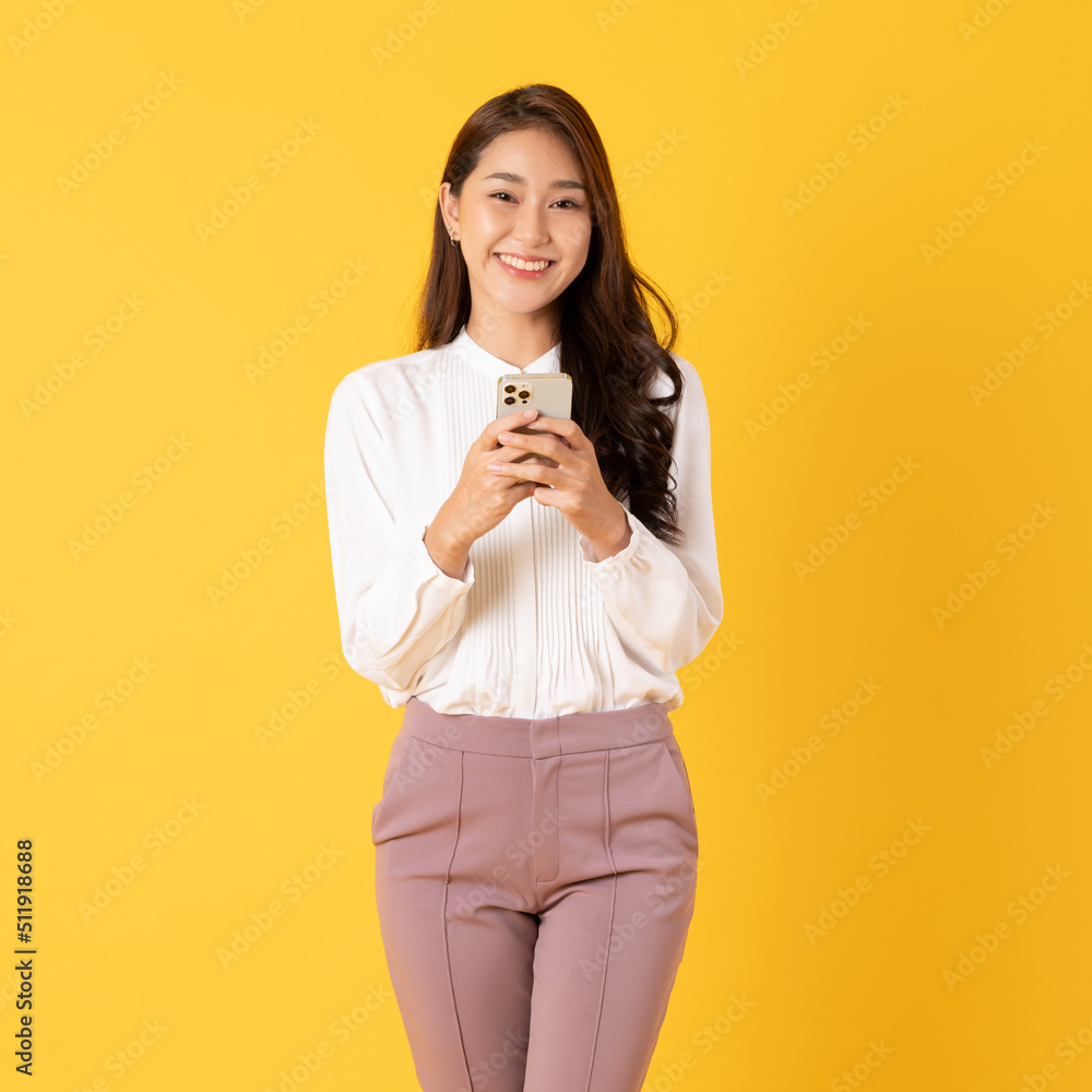 微笑的亚洲女性黄色背景白衬衫使用智能手机
