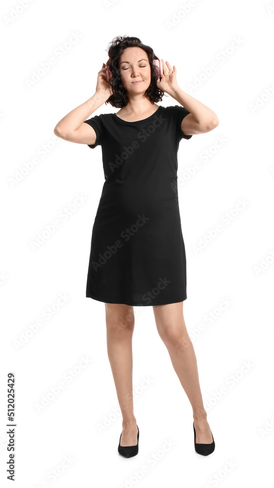 Young pregnant woman in headphones on white background