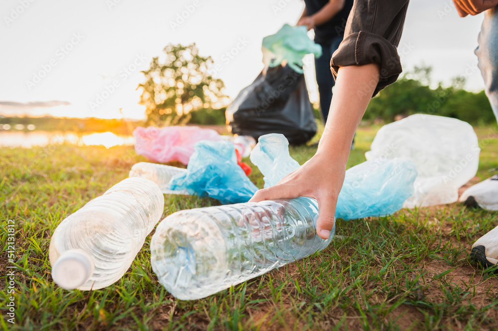 女子在公园用手捡垃圾塑料瓶进行清洁