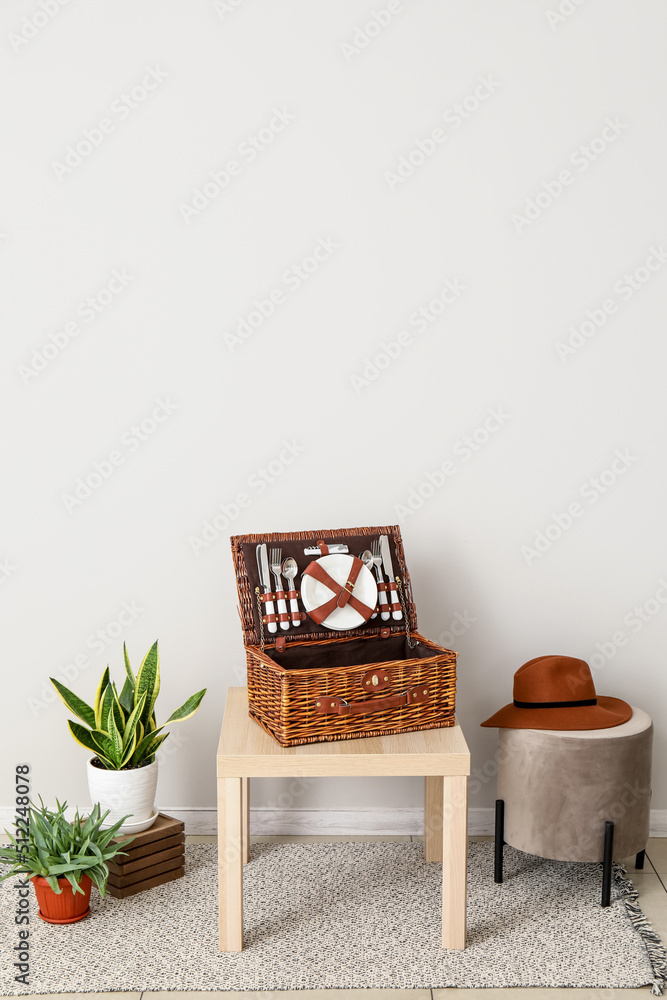 带篮子的桌子，用于野餐、pouf和靠近光墙的室内植物