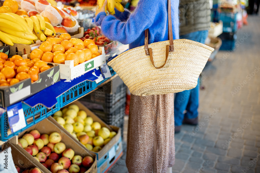 妇女在当地市场用可重复使用的网袋购买水果。无脸裁剪。可持续