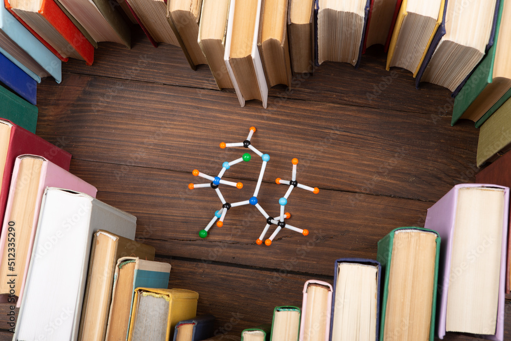 热爱科学概念。书籍以心形和分子模型堆叠在木制桌子上。攻读学位