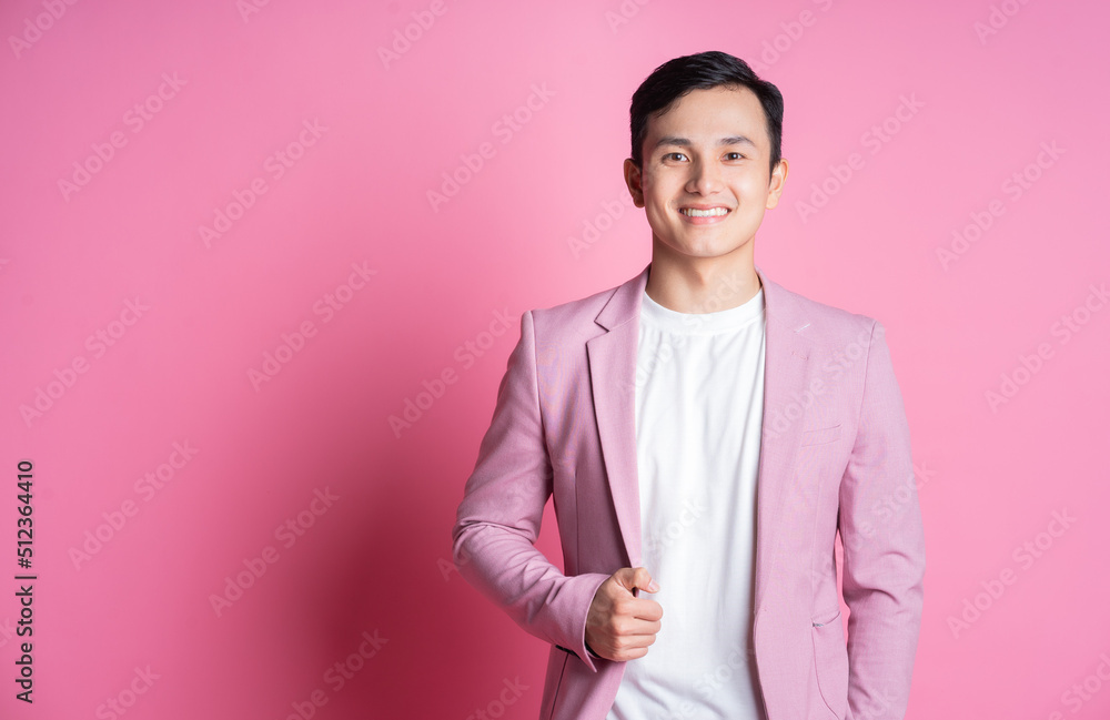 身穿粉色西装的亚洲年轻男子在背景上摆姿势的肖像