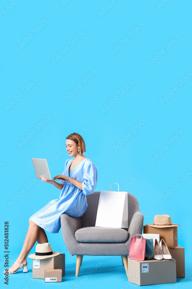 年轻女子，带着笔记本电脑和蓝色背景的新衣服。网上购物