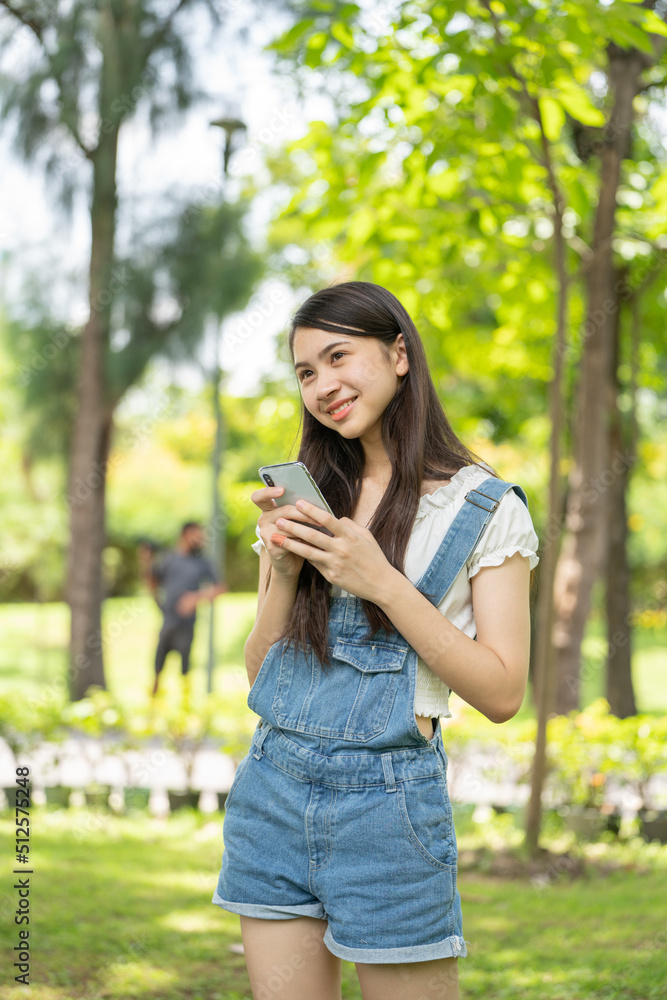 公园里体贴微笑的女人用智能手机，一位年轻迷人的商业女性的画像checki
