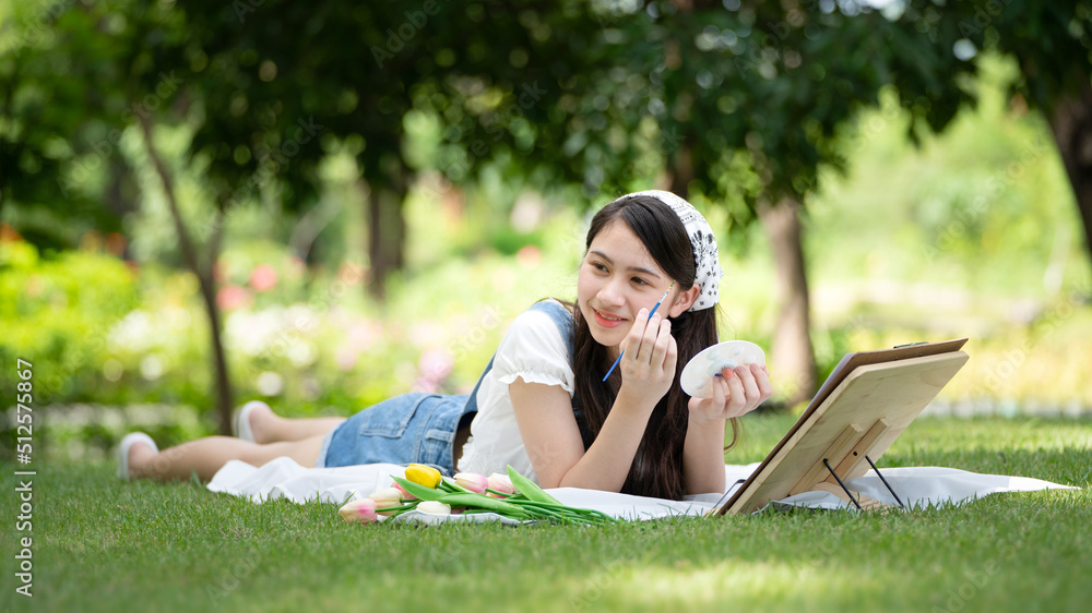 迷人的女孩，在阳光明媚的夏日，坐在公园的格子布上，用水彩完成