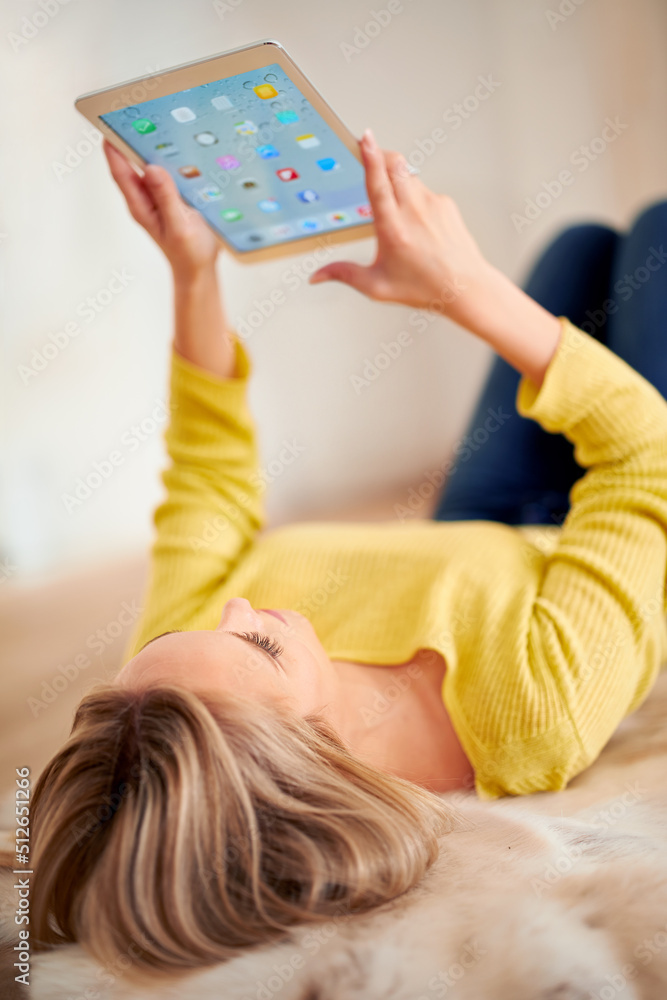 这么多应用程序来陪伴她。一张年轻女子在家使用数字平板电脑的后视照片。