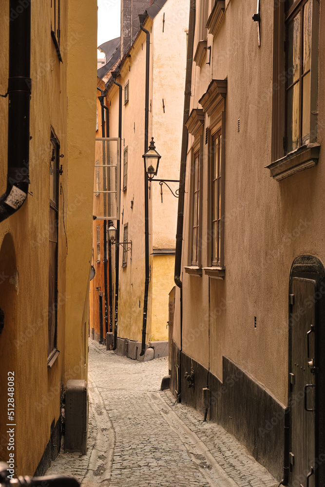 View of an empty, cobble street, alley between city buildings abroad in Stockholm, Gamla Stan. Narro