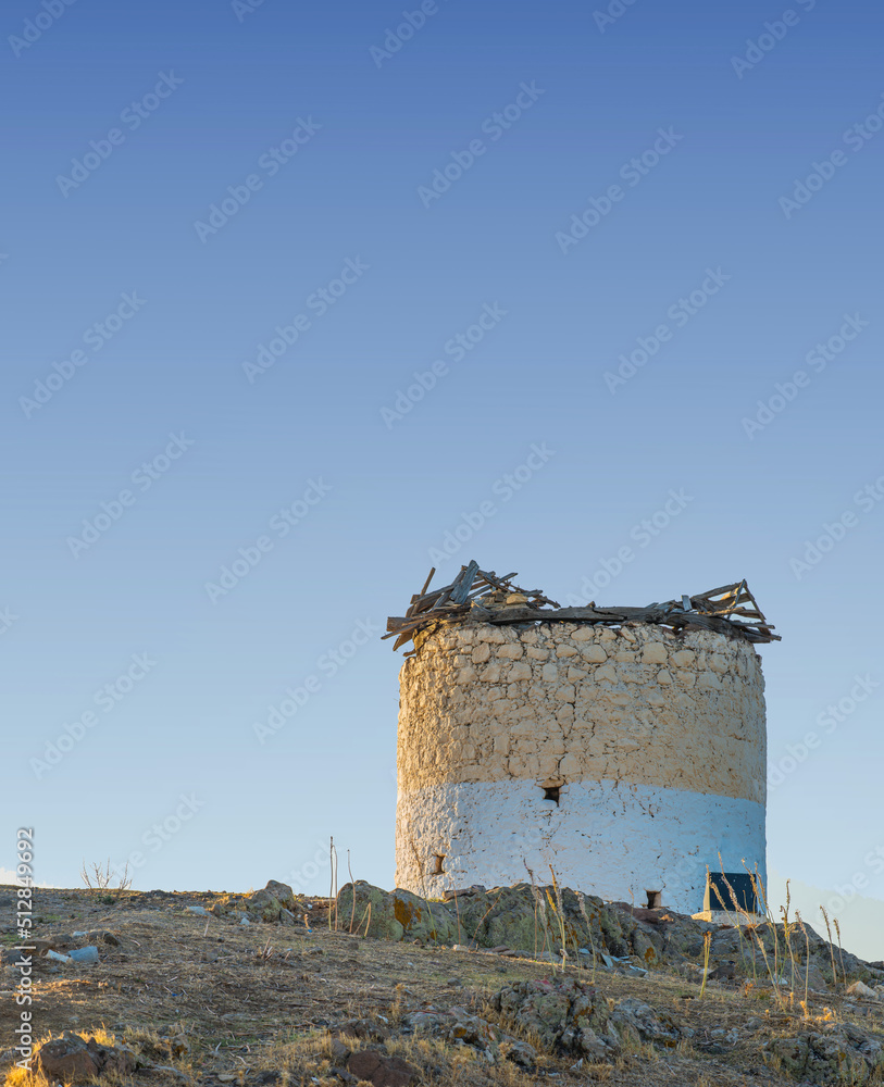 古老的风车，坐落在一座以蓝天为背景的小山上。古老而历史的设计