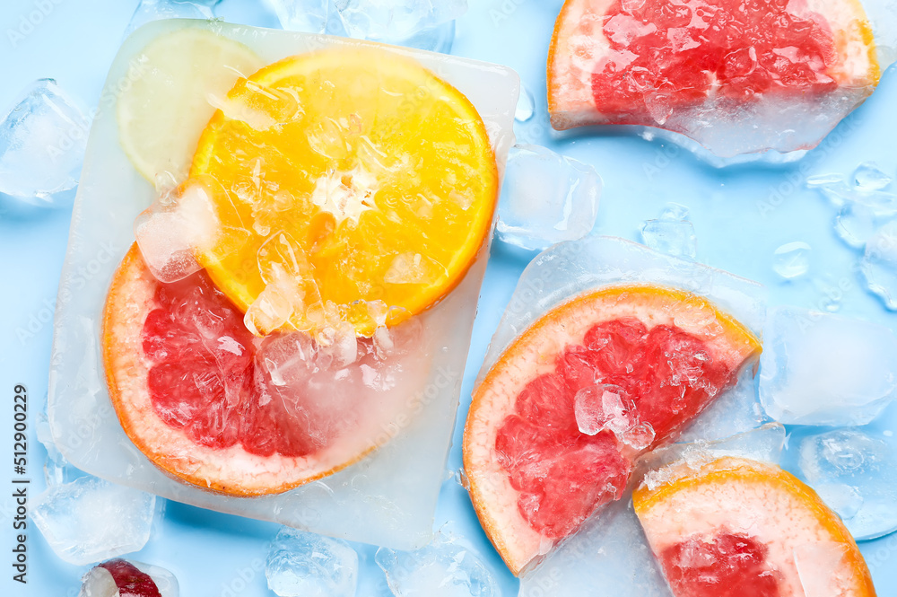 在蓝色背景下冷冻在冰中的新鲜柑橘类水果片