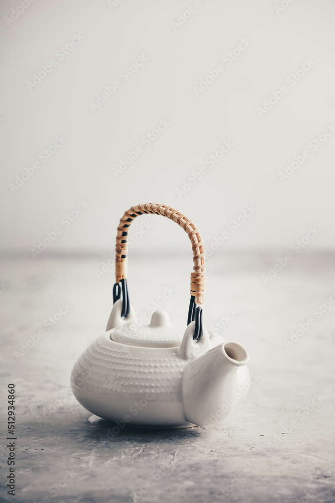 White teapot on rustic stone table against the white wall