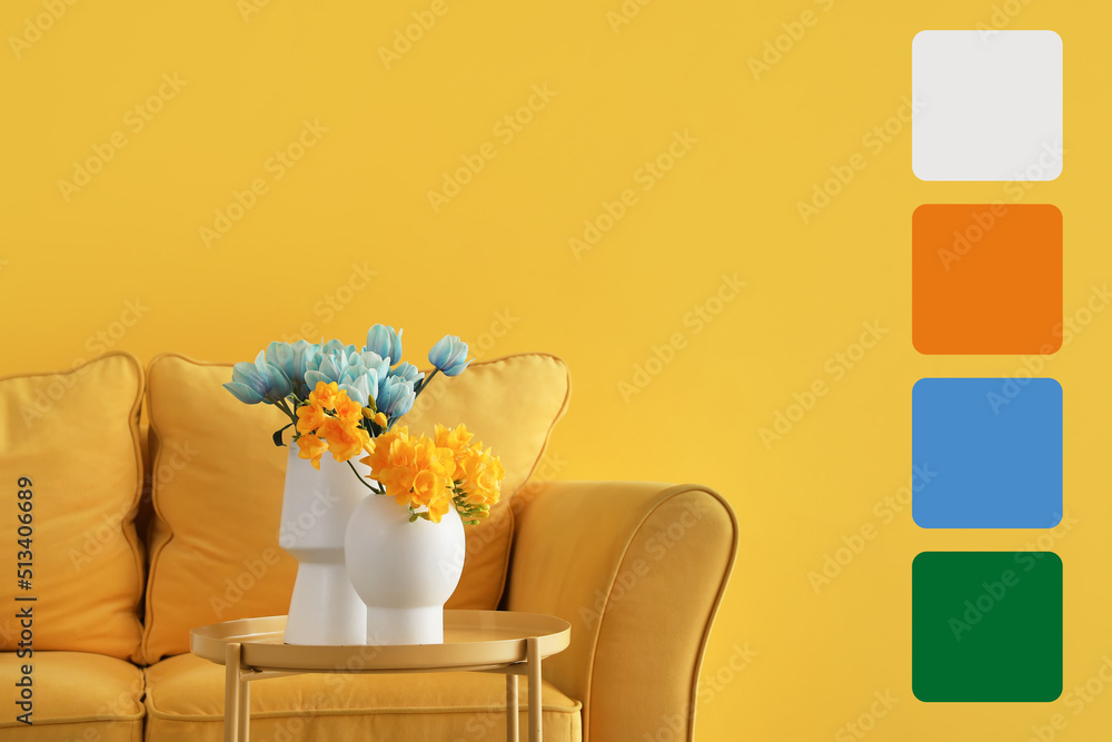 桌子上有漂亮的花，黄色墙壁附近有舒适的沙发。不同的颜色图案