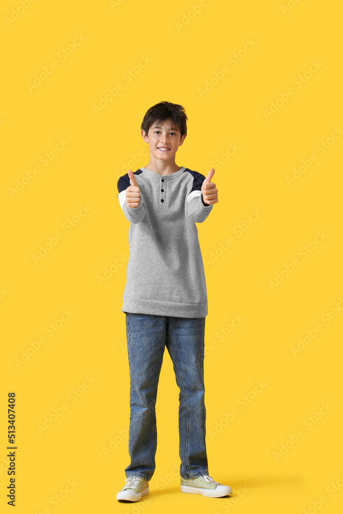 青少年男孩在黄色背景上竖起大拇指