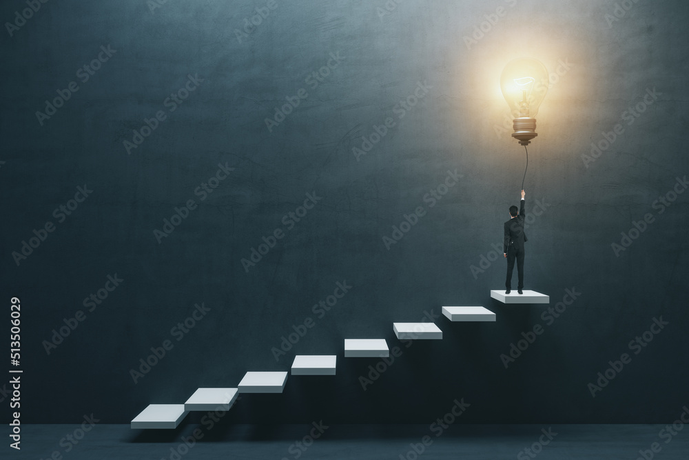 Innovation and idea concept with man in suit back view on the top of white stairway turning on big l