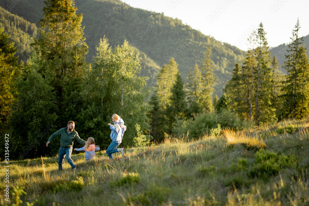 年轻的一家人带着小女孩一起在绿色的草地上行走，同时在山上旅行