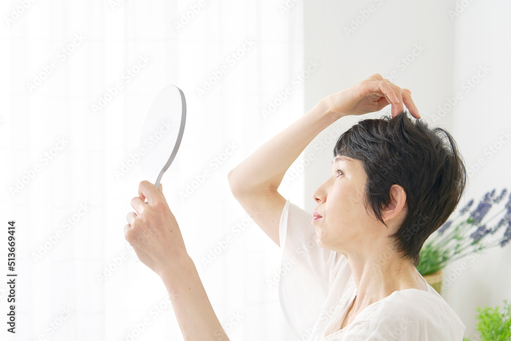自宅で髪の毛を見る中年女性