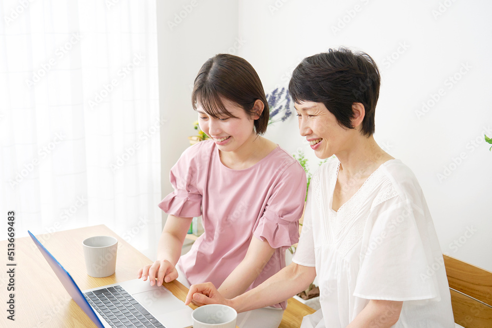 自宅でノートパソコンを見る母親と娘