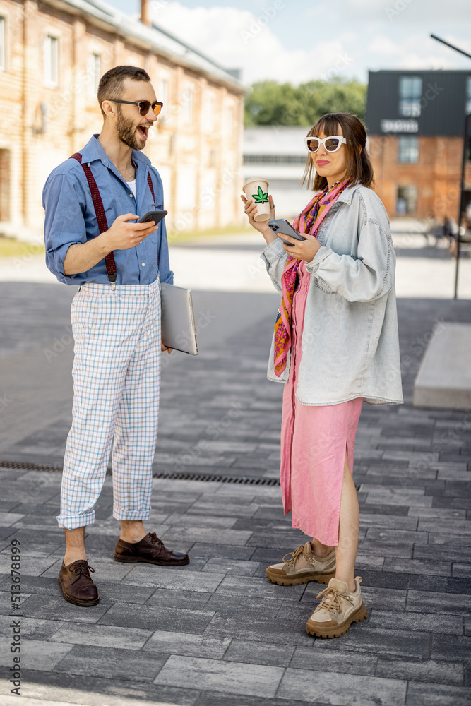 年轻时尚的情侣在喝咖啡时拿着手机站在一起聊天