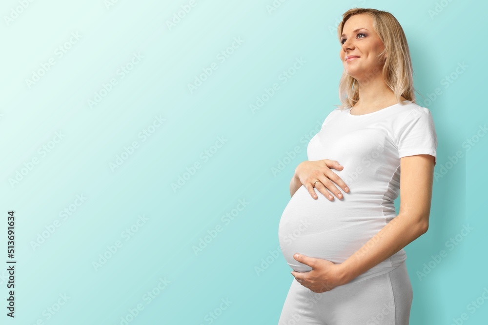 孕妇撑着肚子。健康怀孕概念。蓝色背景上坐着的孕妇，