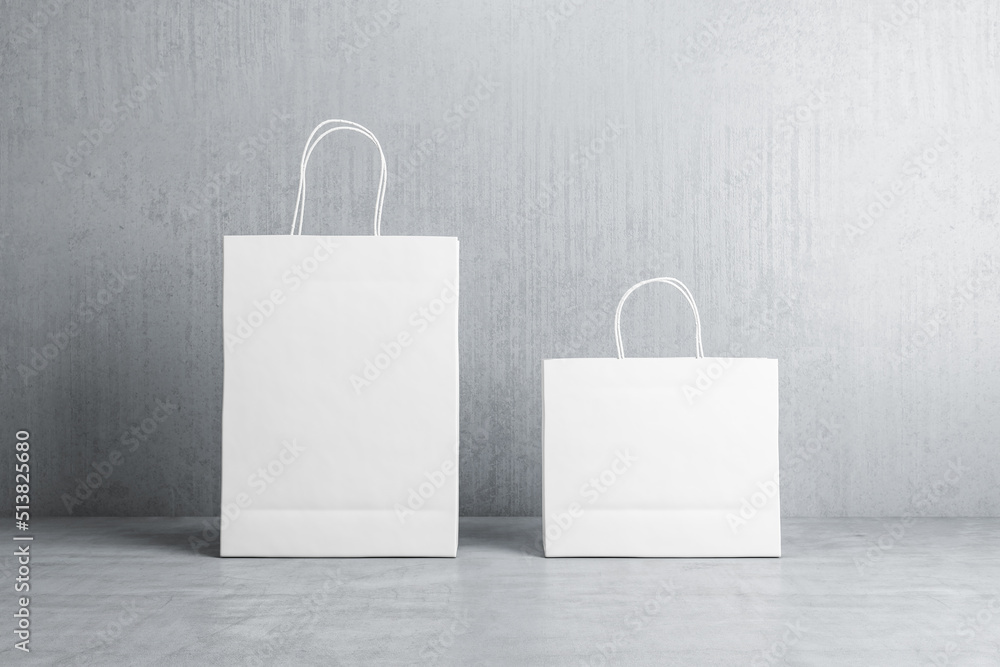 两个空白白色购物袋的正视图，在混凝土地板上放置您的标志或文字