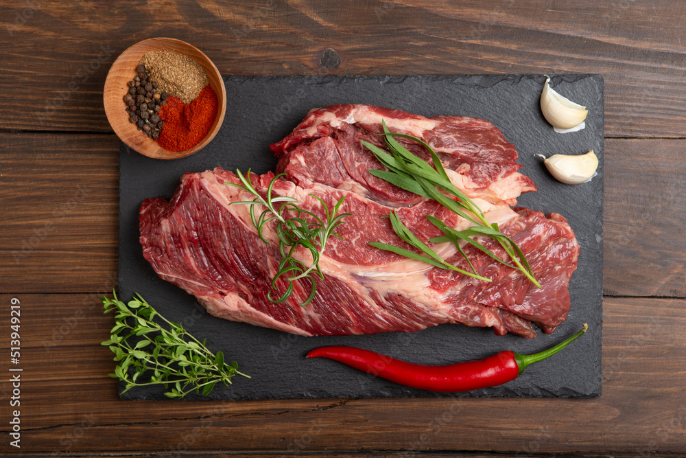 木制桌面上的生牛排。健康食品概念。牛肉块和烹饪烧烤酱的香料