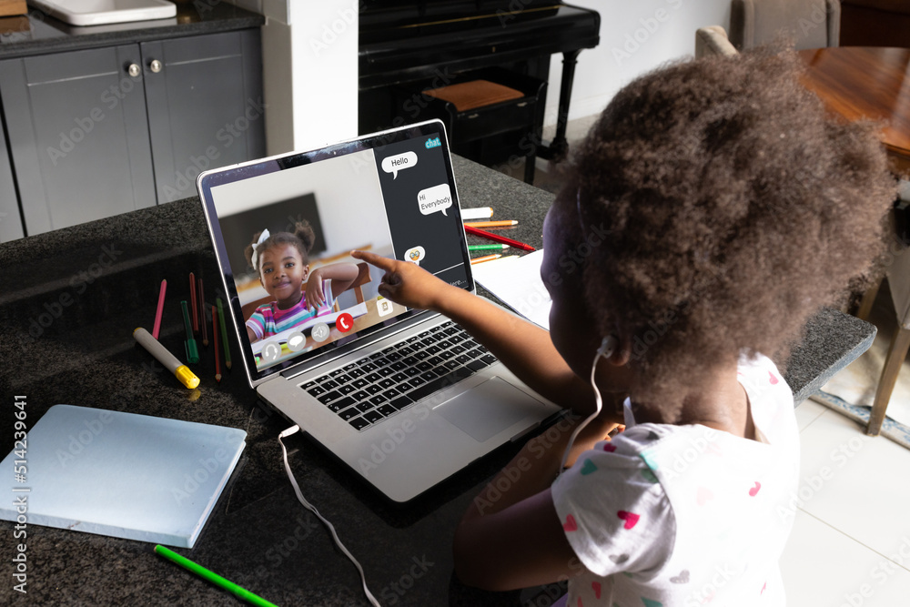 African american girl with afro hair pointing at laptop screen during online class over video call