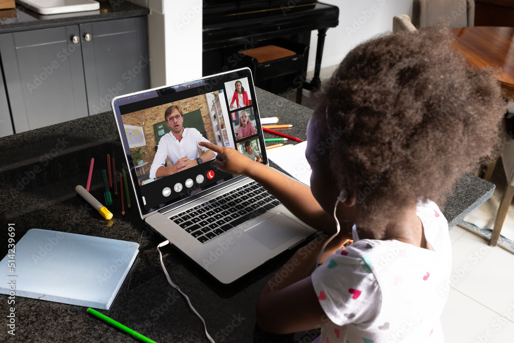留着非洲头发的非裔美国女孩在家里用笔记本电脑指着在线教学的男子