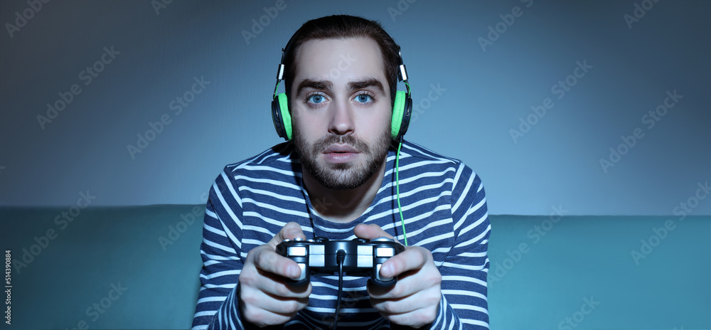 Young man playing video games at home in evening