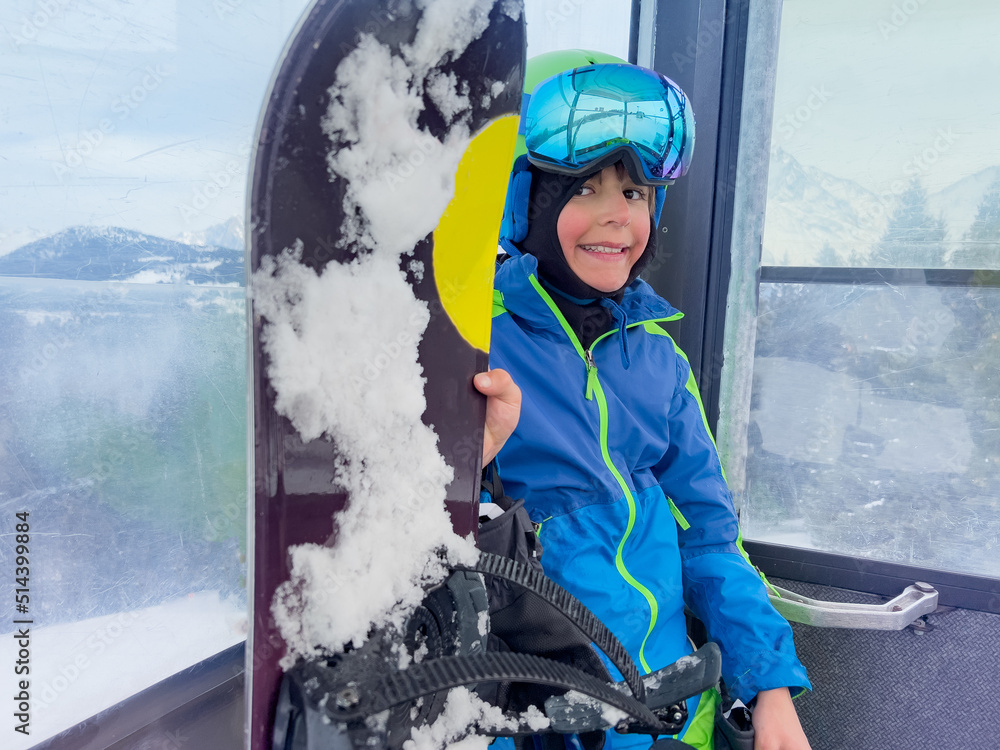 带着滑雪板的微笑男孩站在缆车车厢里