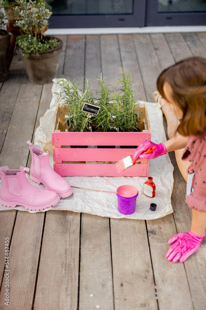 年轻女子将木箱漆成粉红色，在户外露台上做一些翻新家务