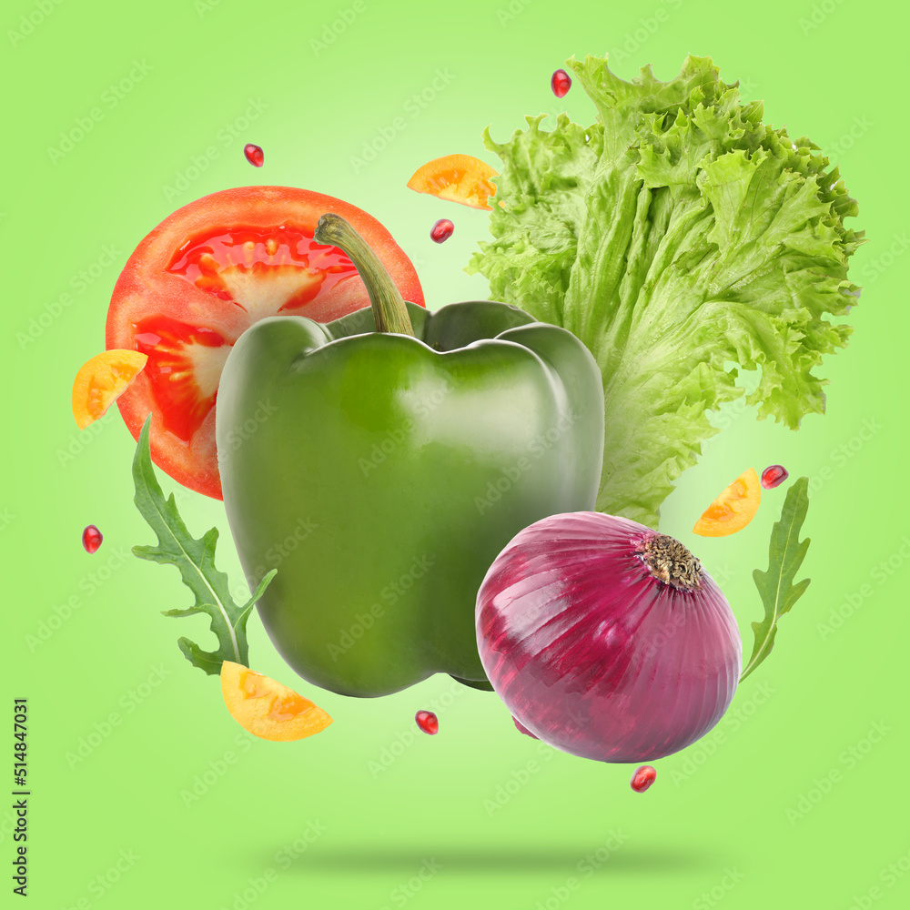 Flying fresh vegetables and herbs on green background