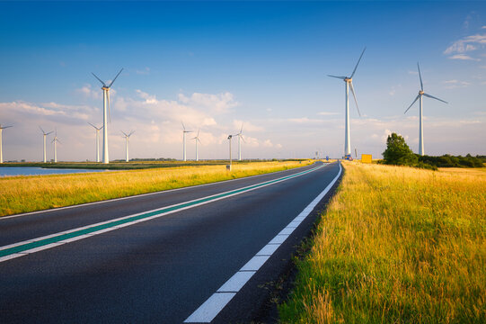 日落时的景观，道路，田野和风力涡轮机。用于能源生产的风车。绿色e