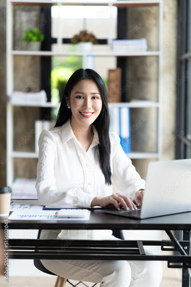亚洲女性在办公室里用笔记本电脑工作。商业金融概念。