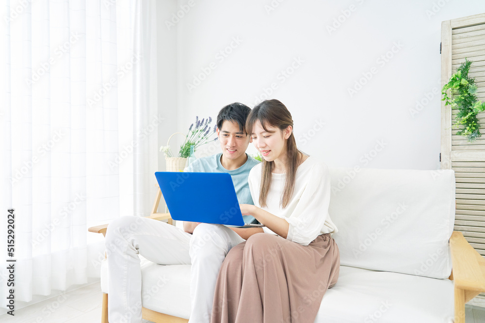 リビングでノートパソコンを見るカップル