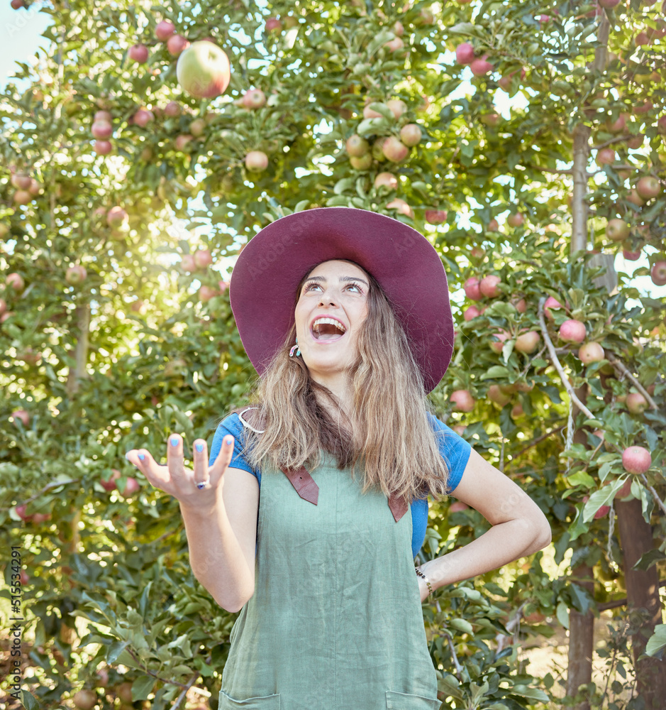 美丽的年轻女农民在收获季节向农场扔苹果。快乐的女人采摘