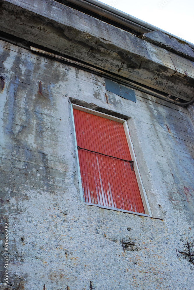 一座石头建筑，位于一处废弃的旧房产上，有一扇红色的门。外部建筑细节o