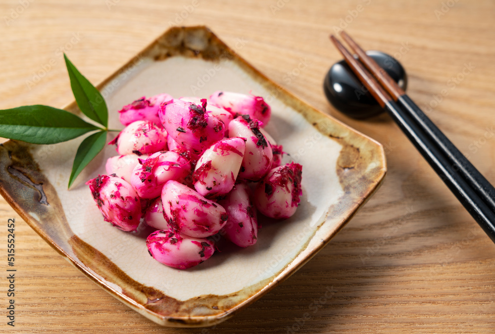Pickled shiso garlic served on a plate placed against a wooden background.