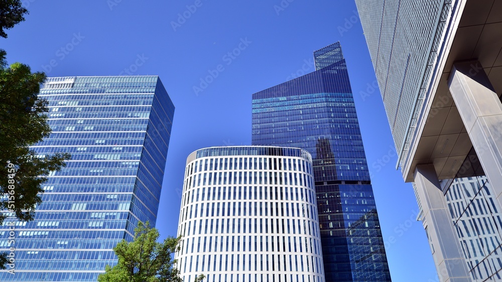 Bottom view of modern skyscraper in business district against blue sky. Looking up at business build