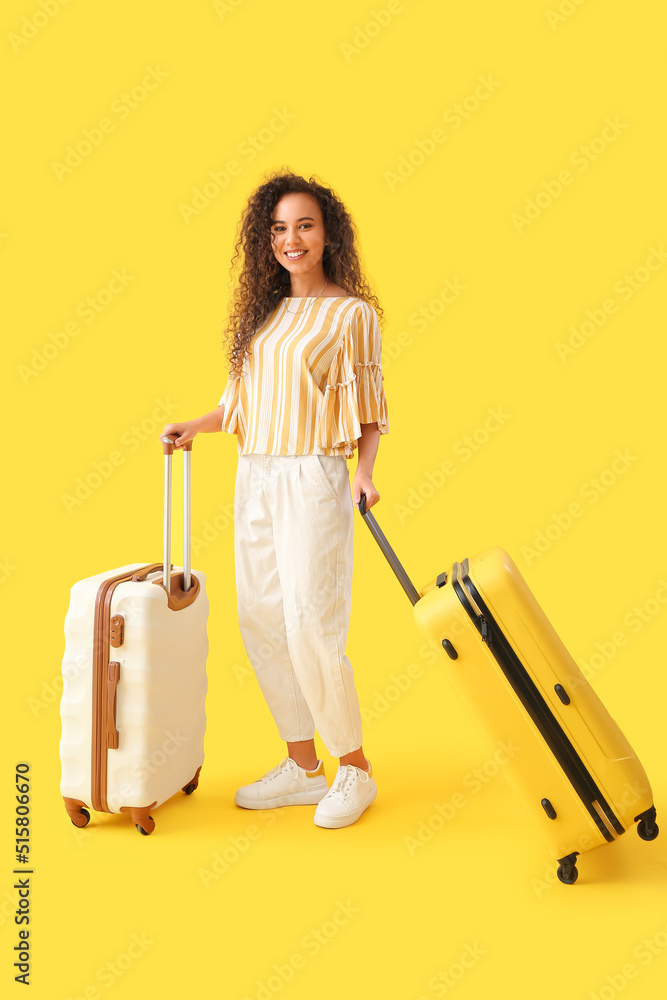 年轻的非裔美国妇女，黄色背景带着行李箱